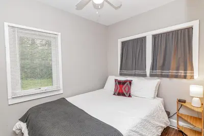 a white bedroom with a bed and two windows at Camelback cottage - on ONE ACRE & near local attractions in Tannersville