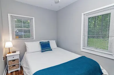 a white bedroom with a bed and two windows at Camelback cottage - on ONE ACRE & near local attractions in Tannersville