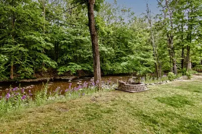 a garden with purple flowers next to a river at Cabin by the Creek with private creek access in Tannersville