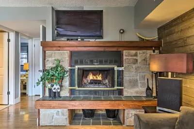 a living room with a stone fireplace with a tv at On Big Boulder Lake Condo with Community Pools! in Lake Harmony