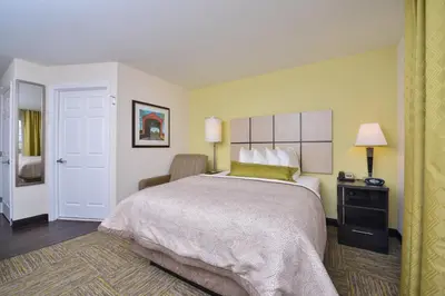 a hotel room with a large bed and a chair at Candlewood Suites Harrisburg-Hershey by IHG in Harrisburg