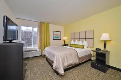 a hotel room with a bed and a flat screen tv at Candlewood Suites Harrisburg-Hershey by IHG in Harrisburg