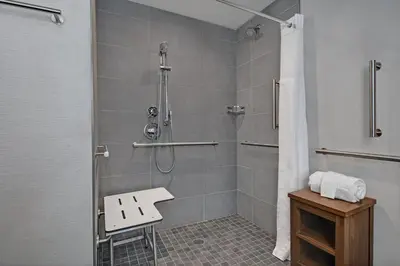 a bathroom with a shower with a bench in it at Courtyard by Marriott Hamilton in Hamilton