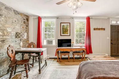 a bedroom with red curtains and a table and a desk at Charming Getaway Less Than 1 Mi to Downtown Lambertville! in Lambertville