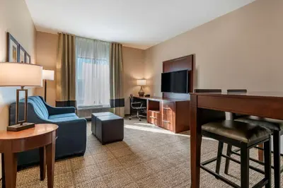 a hotel room with a desk and a living room at Comfort Suites Camp Hill-Harrisburg West in Harrisburg