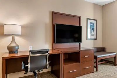 a hotel room with a desk with a television and a chair at Comfort Suites Camp Hill-Harrisburg West in Harrisburg