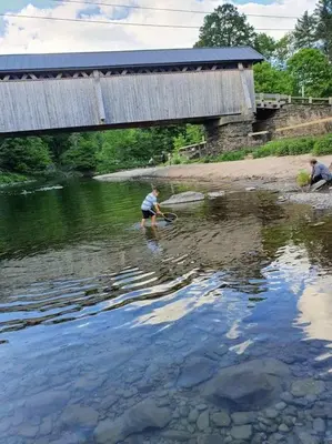 a man standing in the water under a bridge at Trout Town Inn in Roscoe