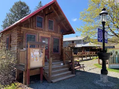 a small log cabin with a sign in front of it at Trout Town Inn in Roscoe
