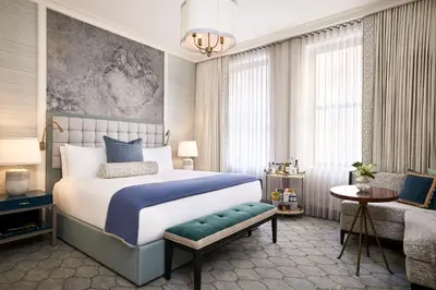 a bedroom with a king sized bed and a chair at The Wall Street Hotel New York City in New York