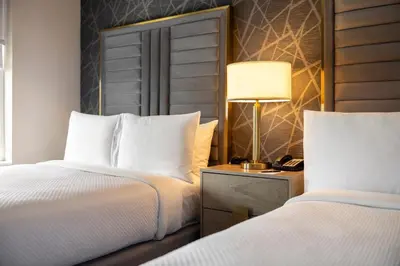 a hotel room with two beds and a lamp at The Chateau Grande Hotel in East Brunswick