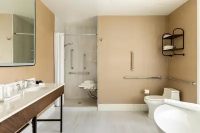 a bathroom with a shower and a toilet and a sink at The Chateau Grande Hotel in East Brunswick