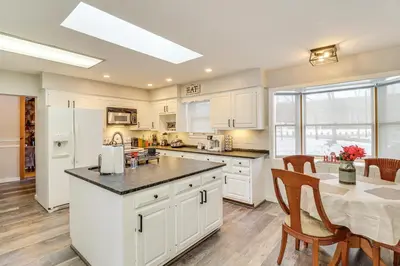 a kitchen with white cabinets and a table with chairs at Hike and Ski Log Cabin in East Stroudsburg! in East Stroudsburg
