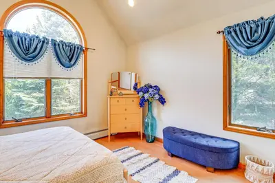 a bedroom with a blue couch and two windows at 4 Mi to Slopes! Split Rock Resort Home with Fire Pit in Lake Harmony