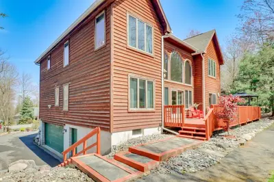 a wooden house with a porch and a fence at 4 Mi to Slopes! Split Rock Resort Home with Fire Pit in Lake Harmony