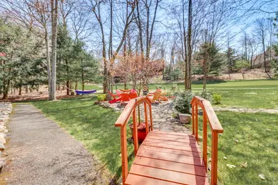 a wooden walkway leading to a park with red chairs at 4 Mi to Slopes! Split Rock Resort Home with Fire Pit in Lake Harmony