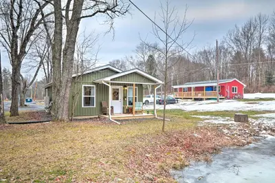 a green tiny house with a red house in the background at Unwind Fireside! Poconos Cottage 12 Mi to Slopes in Brodheadsville