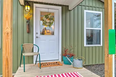 a green house with a chair and a door at Unwind Fireside! Poconos Cottage 12 Mi to Slopes in Brodheadsville