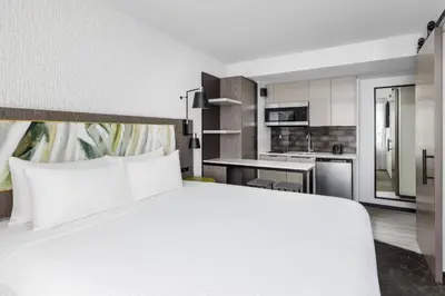 a bedroom with a large white bed and a kitchen at TownePlace Suites by Marriott New York Manhattan/Chelsea in New York