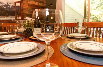 a wooden table with plates and wine glasses on it at Camelback Private Home located behind Waterpark & Ski Lift in Tannersville