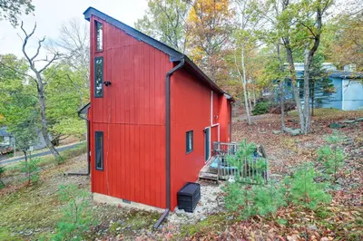 a red shed with a black roof on a hill at Fire Pit and Gas Grill Charming Poconos Abode! in Bushkill