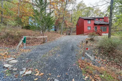a road leading to a red house in the woods at Fire Pit and Gas Grill Charming Poconos Abode! in Bushkill