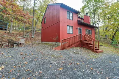 a red house in the woods with a bench at Fire Pit and Gas Grill Charming Poconos Abode! in Bushkill