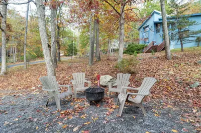 a group of chairs and a grill in the woods at Fire Pit and Gas Grill Charming Poconos Abode! in Bushkill