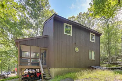 a tiny house in the woods with a porch at Screened Porch and Deck Pet-Friendly Poconos Escape in Lackawaxen