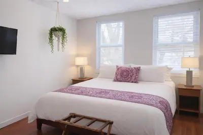 a white bedroom with a large bed and two windows at Artsy Hidden Gem --- FREE PARKING in Philadelphia