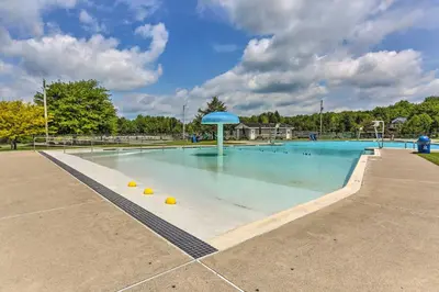 a large swimming pool with a blue umbrella in it at Excellent Lakeview Getaway with Watercrafts Included in Pocono Lake