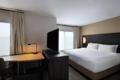 a hotel room with a bed and a desk with a television at Residence Inn New Brunswick Tower Center Blvd. in East Brunswick
