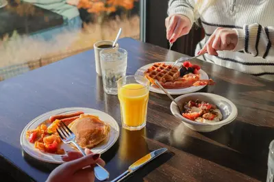 a table with plates of breakfast foods and orange juice at Camelback Resort in Tannersville