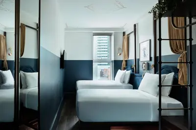 a room with three beds and a window at CIVILIAN Hotel in New York