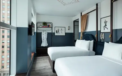 two beds in a hotel room with blue walls at CIVILIAN Hotel in New York