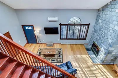 a living room with a staircase and a stone wall at Lake Access and Private Hot Tub at Poconos Home! in White Haven