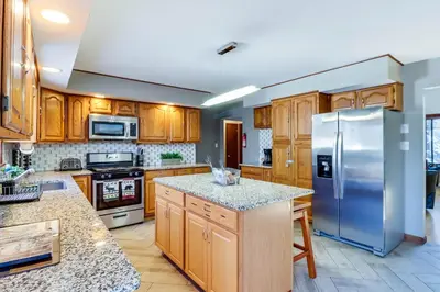 a kitchen with wooden cabinets and a stainless steel refrigerator at Lake Access and Private Hot Tub at Poconos Home! in White Haven