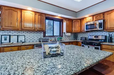 a kitchen with wooden cabinets and a granite counter top at Lake Access and Private Hot Tub at Poconos Home! in White Haven