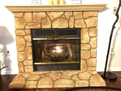 a stone fireplace with a fire in it at Black Bear Lodge @ Middle Creek in Stevens
