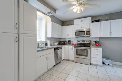 a kitchen with white cabinets and a ceiling fan at 8 Mi to Liberty Bell! Spacious and Charming Home in Upper Darby