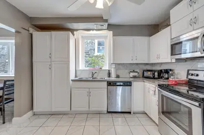 a kitchen with white cabinets and a sink at 8 Mi to Liberty Bell! Spacious and Charming Home in Upper Darby