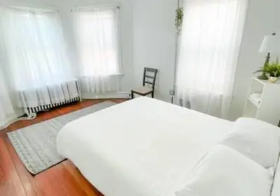 a white bedroom with a bed and a chair at Legacy - Spring Garden University City in Philadelphia
