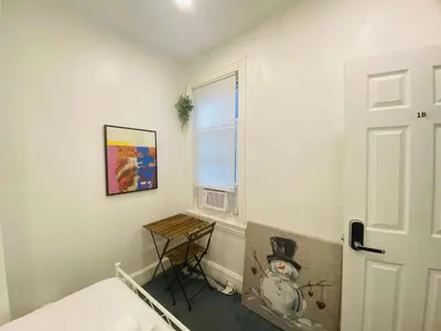 a bedroom with a bed and a table next to a window at Oui on Ludlow - Entire House and Private Rooms in University City in Philadelphia