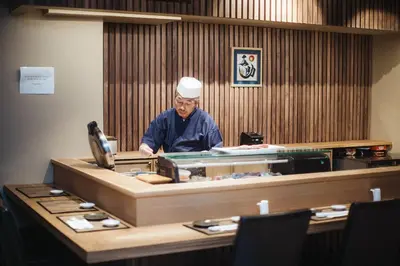 a chef standing behind a counter in a restaurant at Henn na Hotel New York in New York