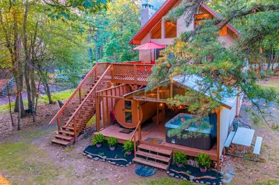 a tree house with a swimming pool in front of it at 3 Mi to Slopes! Poconos Chalet with Hot Tub and Sauna in Lake Harmony
