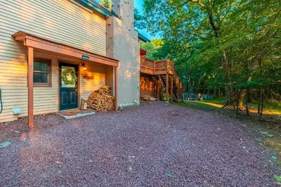 a house with a driveway next to a building at 3 Mi to Slopes! Poconos Chalet with Hot Tub and Sauna in Lake Harmony