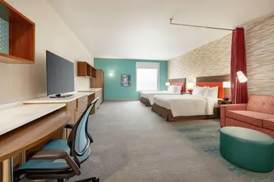 a hotel room with a bed and a desk with a television at Home2 Suites by Hilton New Brunswick, NJ in New Brunswick
