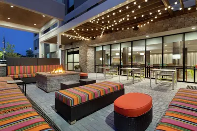 an outdoor patio with a fireplace and tables and chairs at Home2 Suites by Hilton New Brunswick, NJ in New Brunswick