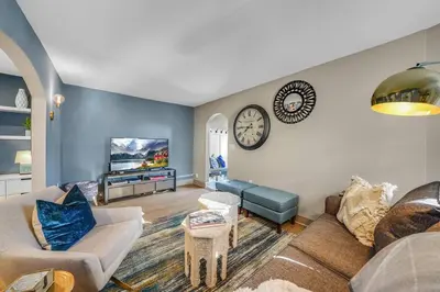 a living room with a couch and a clock on the wall at Luxury Apartment in Historic Carriage House in Kennett Square