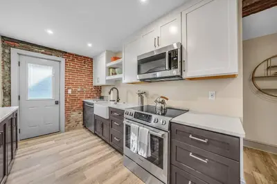 a kitchen with stainless steel appliances and a brick wall at Luxury Apartment in Historic Carriage House in Kennett Square