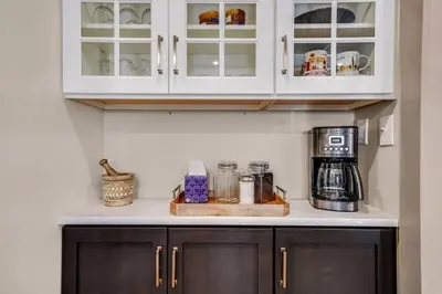 a kitchen counter with white cabinets and a coffee maker at Luxury Apartment in Historic Carriage House in Kennett Square